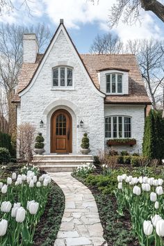 a white brick house with tulips in the front yard and walkway leading to it