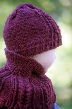 a small child wearing a purple knitted hat and scarf on top of his head