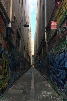 an alleyway with graffiti on the walls and street lights hanging from the buildings above