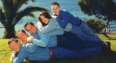 four people are posing for a photo in front of the water and palm trees with their arms around each other