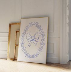 two framed pictures sitting next to each other on the floor in front of a white wall