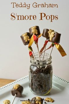 there are chocolate candies and marshmallows in a mason jar with the words, teddy graham s'more pops