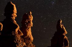 the night sky is filled with stars above some rock formations and trees in the foreground