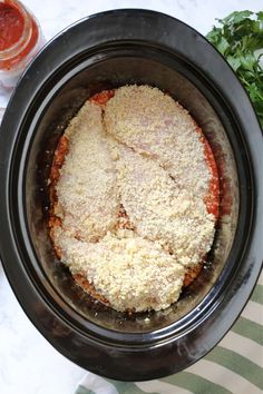 a crock pot filled with meat and sauce on top of a striped table cloth