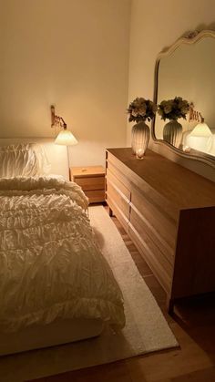 a bedroom with a bed, dresser and mirror