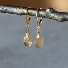 Sparkly and gorgeous, teardrops of Golden Rutilated Quartz hang from secure, hinged-back ear wires (the back of the ear wire clicks into place, making the earrings impossible to lose when you're wearing them). These are lightweight earrings that will wear easily. Golden Rutilated Quartz, also known as Angel's Hair Quartz, is a clear quartz with fine, gold needles or strands of inclusion visible inside. These needles or "rutiles" are minerals containing titanium oxide. It's a truly eye-catching stone that is thought to help the wearer increase mental clarity and aid in decision making. The earrings measure a total length of 1.25 inches. Anniversary Briolette Teardrop Gemstone Earrings, Fine Jewelry Teardrop Earrings For Everyday, Faceted Teardrop Drop Earrings For Anniversary, Everyday Teardrop Faceted Earrings, Everyday Teardrop Fine Jewelry Earrings, Dainty Teardrop Earrings With Lever Back, Yellow Gold Gemstone Teardrop Earrings, Dainty Teardrop Gemstone Earrings, Elegant Everyday Gemstone Teardrop Earrings