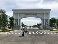 two people standing in the middle of an empty street under a large arch that says vendoes star city