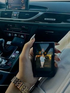 a woman is holding up her cell phone to take a photo in the car while driving