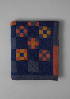 a blue and orange quilt with squares on it's sides, sitting on a gray surface