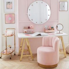 a desk with a chair, mirror and pictures on the wall in a pink room