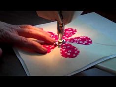 someone cutting paper with scissors on top of a piece of paper that looks like a flower