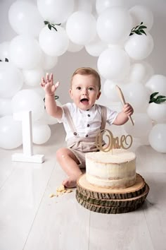 a baby sitting in front of a cake with the number one on it