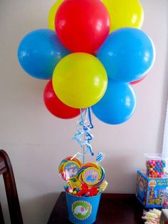 a bunch of balloons that are on top of a table with some candy in it