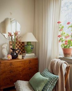 a room with a dresser, mirror and vase on it's shelf next to a window