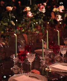 the table is set with candles, plates and flowers in glass vases on it