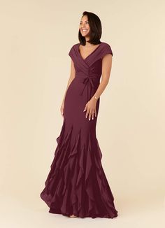 a woman in a long purple dress smiling and looking off to the side with her hands on her hips