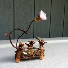 a flower that is sitting on top of a piece of wood with branches and flowers growing out of it