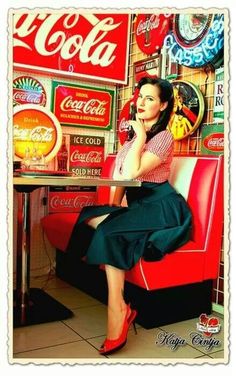 a woman sitting on top of a red chair in front of coca cola signs and neon signs