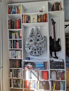 a book shelf filled with lots of books and a star wars millennium clock on top of it