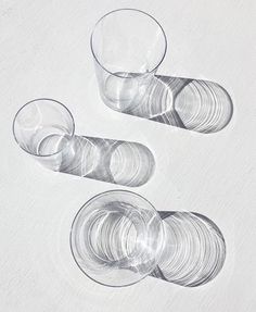 three clear glasses sitting next to each other on a white table top with circles in the middle