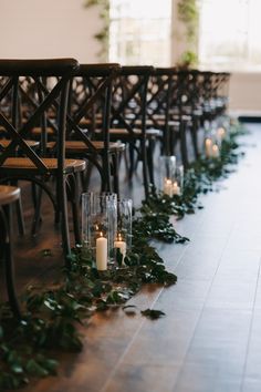 rows of chairs lined up with candles and greenery on the floor in front of them