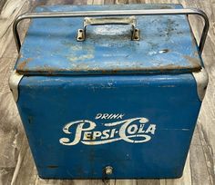 an old pepsi cola cooler sitting on top of a wooden floor next to a wall