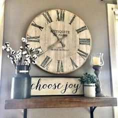 a large clock mounted to the side of a wall above a shelf with vases and flowers