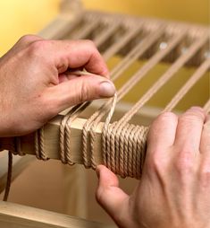 two hands on a hammock stringing the strings to make it look like they are weaving