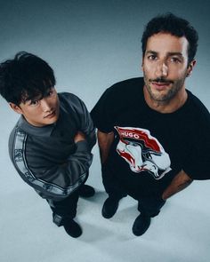 two men are posing for the camera in front of a gray background