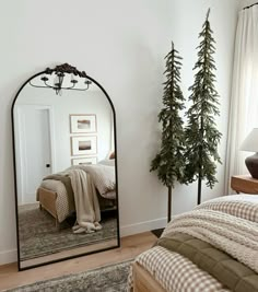 a bedroom with a bed, mirror and christmas trees in the corner on the wall