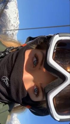 a woman wearing ski goggles standing in the snow