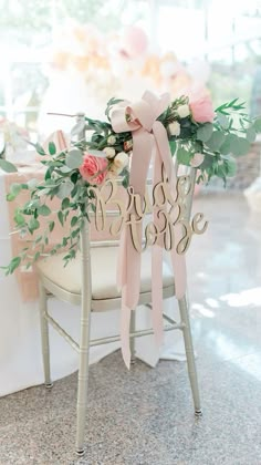 a chair decorated with pink flowers and greenery is adorned with a bow that says bride