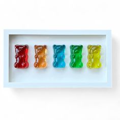 four gummy bears in a white shadow box