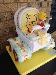 a winnie the pooh diaper cake on top of a yellow table next to a teddy bear