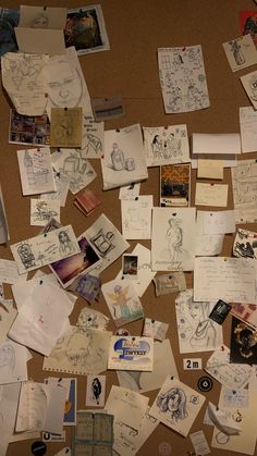 many papers and pictures are spread out on the floor, including one that is covered with paper