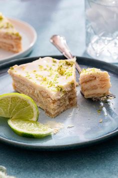 there is a piece of cake on the plate with limes and a fork next to it