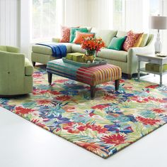 a living room filled with lots of furniture and flowers on top of a colorful rug