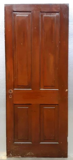 an old wooden door with no glass on the top and bottom panel, in front of a white wall