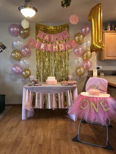 a birthday party set up with balloons, cake and decorations on a table in the middle of a room