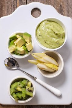 three small bowls filled with different types of food on a white tray next to two spoons