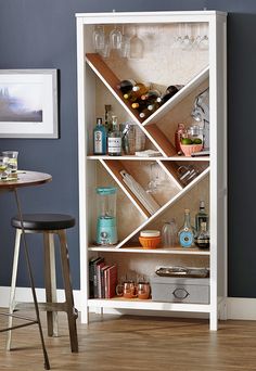 a white bookcase with shelves filled with bottles and glasses next to a bar stool