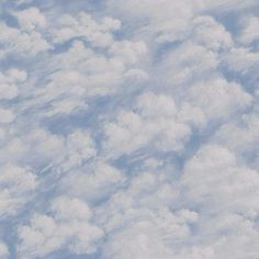 an airplane is flying high in the sky with fluffy clouds above it, as seen from below