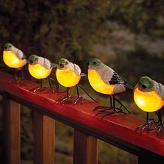 five birds are sitting on a rail with glowing lights in the shape of their heads