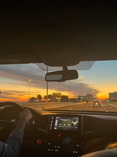 a person driving a car on a highway at sunset