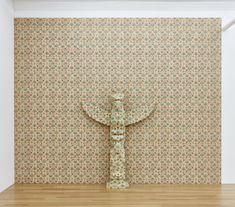 an installation in a gallery of an Indonesian replica of an Alaskan totem pole, coated in floral wallpaper Art