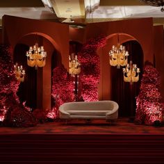 a room with red flowers and chandeliers on the walls, along with a white couch