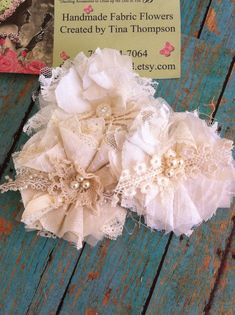 two pieces of fabric and lace sitting on top of a wooden table next to a business card