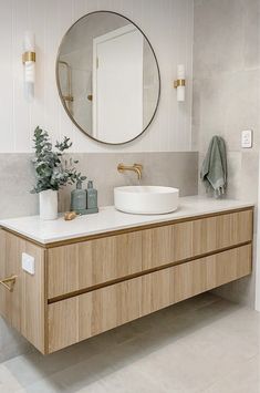 a bathroom with a sink, mirror and plants on the counter top in front of it