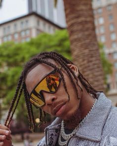 a man with dreadlocks and sunglasses looking at his cell phone