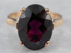 "Always popular and never out of style, this vintage ring is a modestly sized cocktail piece that is easy to wear day or evening! The center stone is a bright grape garnet with sumptuous flashes of violet, cabernet, and berry pink. The airy design of the undercarriage lets plenty of light flow through the stone! Metal: 14K Yellow Gold Gem: Grape Garnet 7.11 Carats Gem Measurements: 10.5 x 14.4 mm, Oval Ring Size: 7.50 Marks: \"14K\" Stamped on the inside band SKU #: 005P394A Each piece has been Purple Ruby Ring For Formal Occasions, Formal Garnet Burgundy Ring, Classic Burgundy Ruby Ring For Formal Occasions, Formal Burgundy Garnet Ring, Formal Purple Ruby Ring With Center Stone, Formal Purple Ruby Ring, Classic Formal Burgundy Rings, Formal Purple Oval Ruby Ring, Garnet Gold Ring